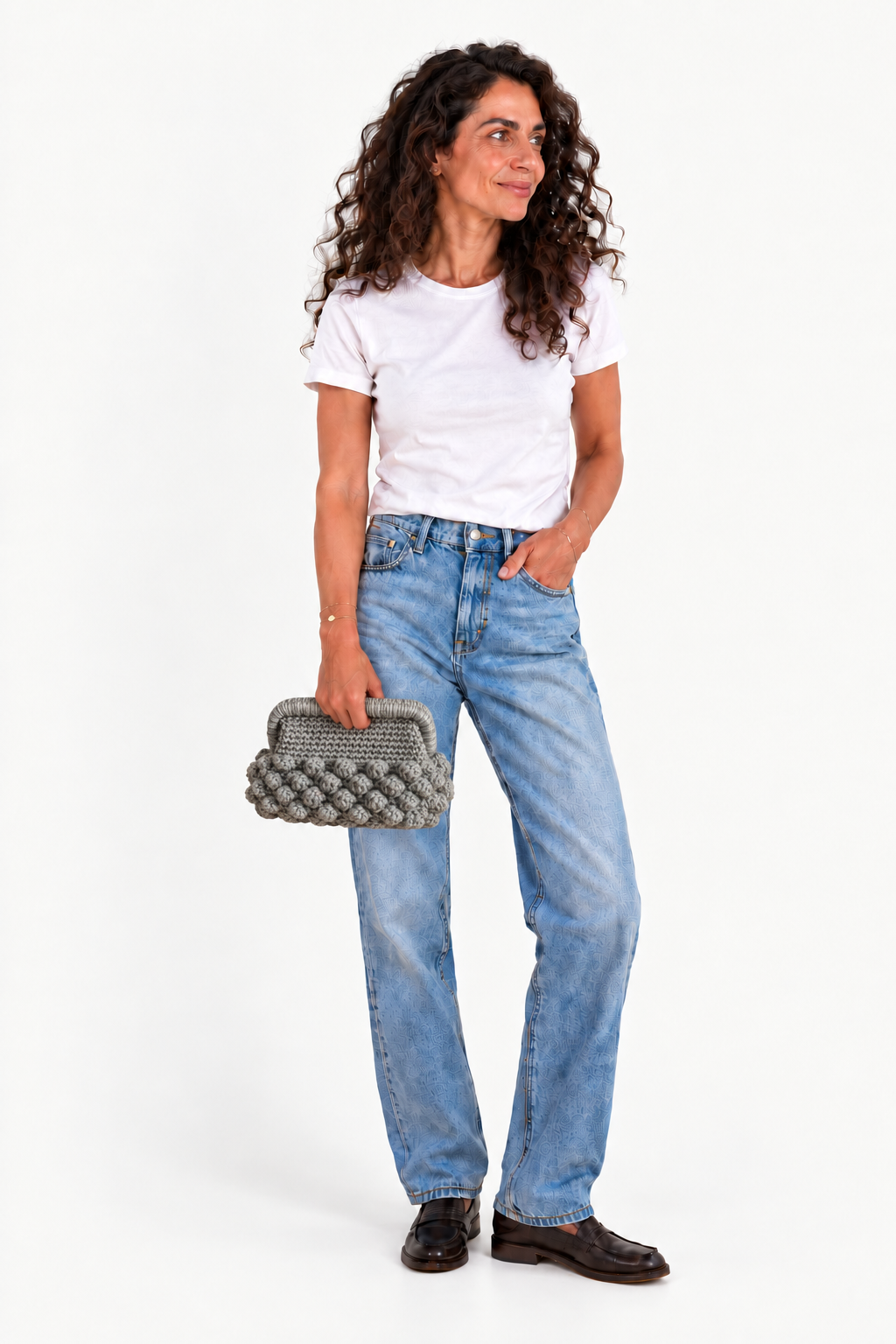 KOUKLA woman in a white tee and light-wash jeans holding NAXOS STEEL with its straight rectangular wrapped frame and grey crochet bobble detailing.